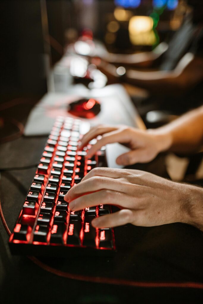 A close-up shot of a gamer's hands using a mechanical gaming keyboard with red backlighting.