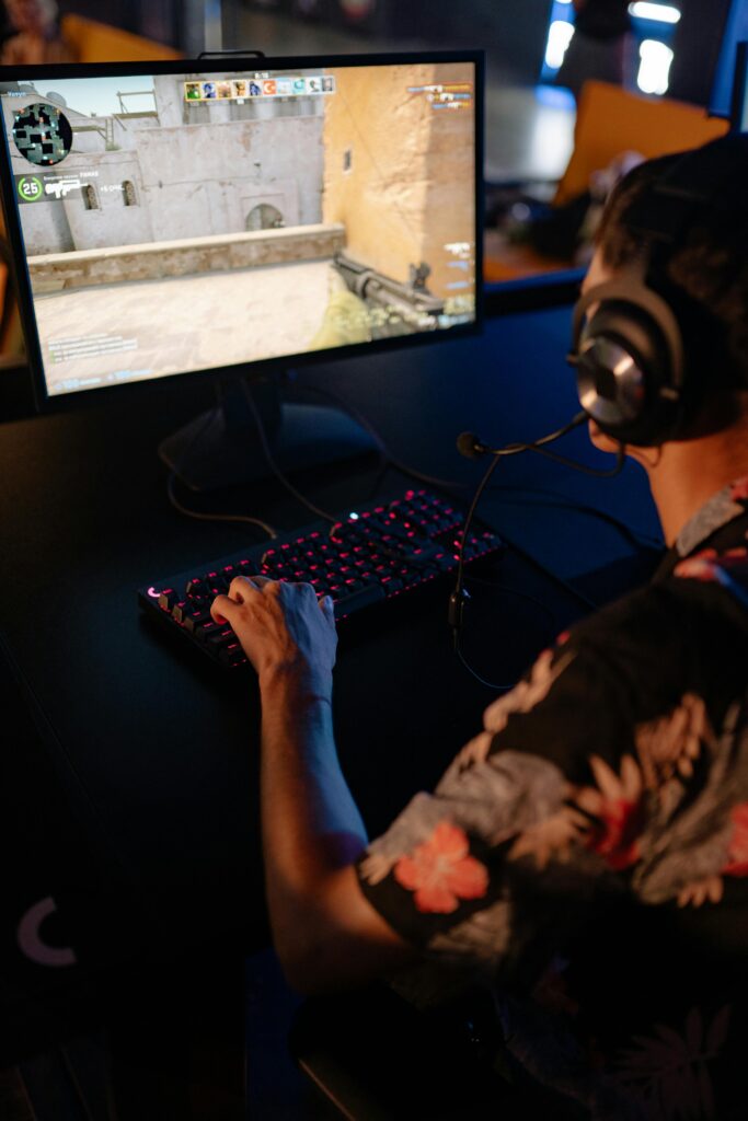 A young man in a floral shirt is focused on a gaming session, highlighting immersive entertainment.